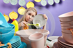 Sad girl feds up cleaning and washing in the kitchen with blue wall