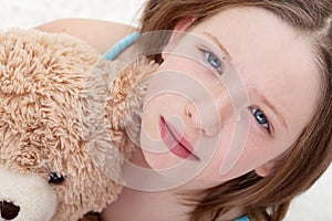 Sad girl holding teddy bear and crying