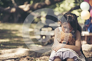 Sad girl hugging teddy bear sadness alone in green garden park. Lonely girl feeling sad unhappy sitting outdoors with best friend
