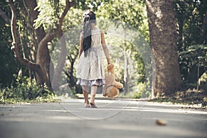 Sad girl hugging teddy bear sadness alone in green garden park. Lonely girl feeling sad unhappy walking outdoors with best friend