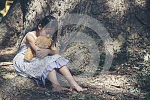Sad girl hugging teddy bear sitting under tree sadness alone in green park. Lonely girl feeling sad unhappy sit outdoors hug best