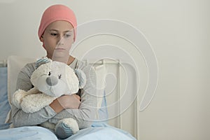 Sad girl with leukemia hugging plush toy in the hospital