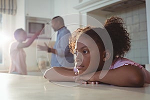 Sad girl listening to her parents arguing in kitchen