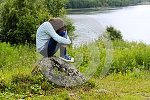 The sad girl with long hair sits on a stone. Concept depression