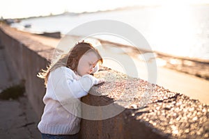 Sad girl with long hairs near river, childhood