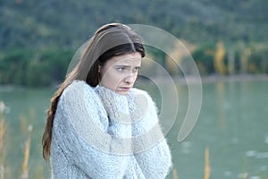 Sad girl looking away in a lake in winter