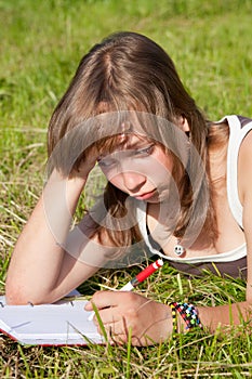 Sad girl is lying on green grass