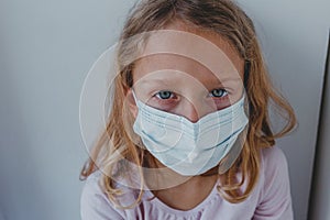 A sad girl in quarantine with a mask looks with blue eyes. portrait close-up. covid