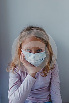 A sad girl in quarantine with a mask looks with blue eyes. portrait close-up. covid