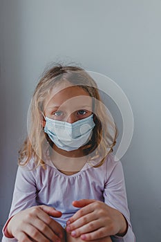 A sad girl in quarantine with a mask looks with blue eyes. portrait close-up. covid