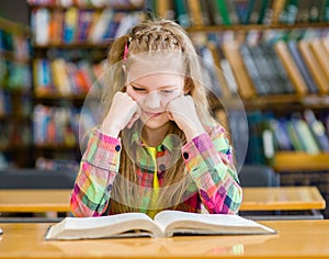 Sad girl reading a book in the library