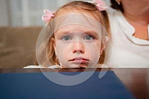 sad girl sits leaning on chin against table and waiting for order in cafe.