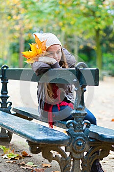 Sad girl sitting on a bench in park