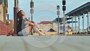 Sad girl sitting on the tiles of the railway station and crying.