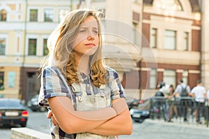 Sad girl teenager with arms crossed on a city street