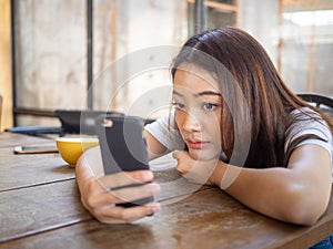 The sad girl is waiting for a phone call or text message from her boyfriend. Sitting lonely and anxious in a coffee shop