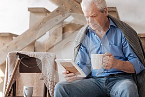 Sad grey haired man drinking tea