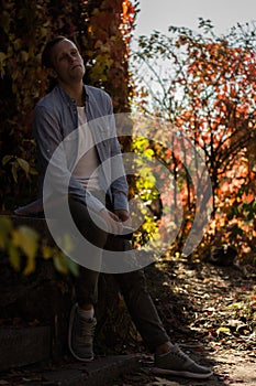 Sad guy with phone in casual clothes in the autumn park