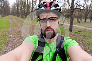 Sad guy in sportswear and helmet taking selfie on nature