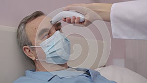 Sad ill elderly man in isolation at home wearing a handmade virus protection mask.