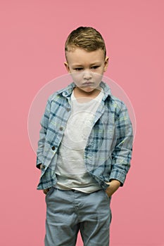 Sad kid posing on pink background. Vertical photo.