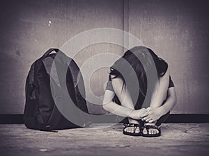 Sad Kid sitting on the floor with school bag waiting for parent.