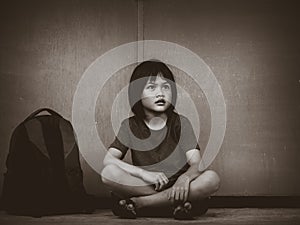 Sad Kid sitting on the floor with school bag waiting for parent.