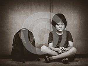Sad Kid sitting on the floor with school bag waiting for parent.