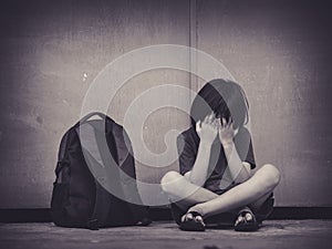 Sad Kid sitting on the floor with school bag waiting for parent.