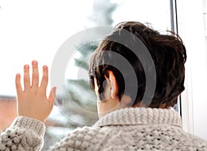 Sad kid on window and winter snow