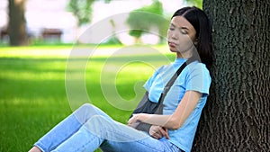 Sad lady with injured arm in supporting sling sitting tree in park, medicine