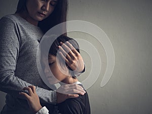 Sad little boy being hugged by his mother at home.