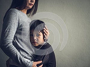 Sad little boy being hugged by his mother at home. photo