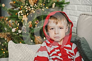 Sad little boy and Christmas tree, natural decor. photo