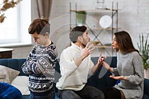 Sad little boy feels upset while his parents fighting at background. Mother and father quarrel. Family conflicts and