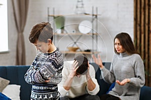 Sad little boy feels upset while his parents fighting at background. Mother and father quarrel. Family conflicts and