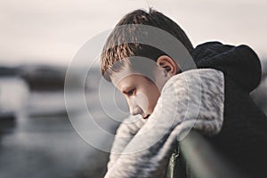 Sad little boy leaning over railing