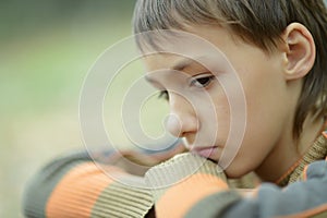 Sad little boy outdoors in autumn