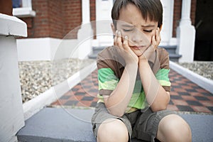 Sad Little Boy Sitting On Front Steps