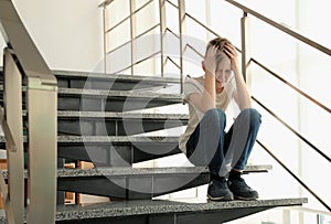 Sad little boy sitting on stairs