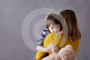 Sad little child, boy, hugging his mother at home