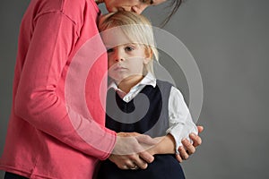 Sad little child, boy, hugging his mother at home, isolated image, copy space