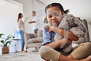 Sad, little girl and crying from parent fight, argument or divorce hugging teddy at home. Unhappy young child in