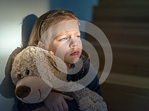 Sad little girl embracing her teddy bear - feels lonely