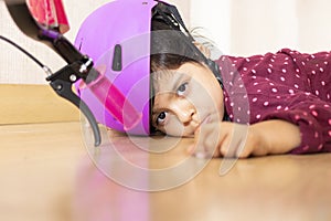 Sad little girl fell to the ground while playing with her bicycle in the floor