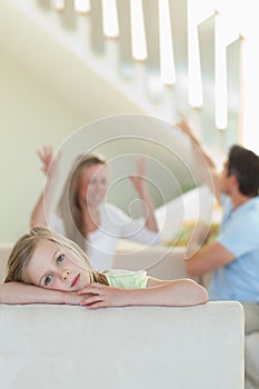 Sad little girl with fighting parents behind her