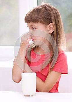 Sad little girl with a glass of milk