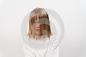 sad little girl with hair covers the face on a white background.