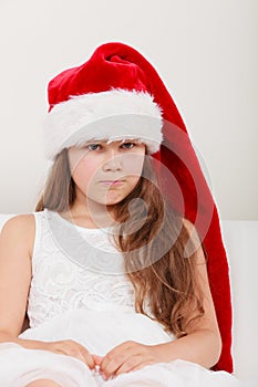 Sad little girl kid in santa claus hat. Christmas.