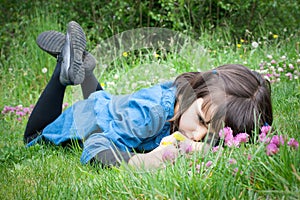 Sad little girl lying in the grass